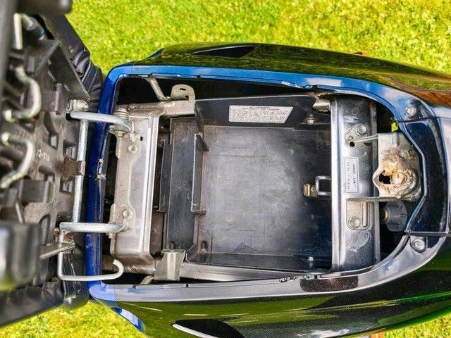 Öffnen Sie das Staufach eines blauen Motorrads und geben Sie den Blick auf das Innere frei.