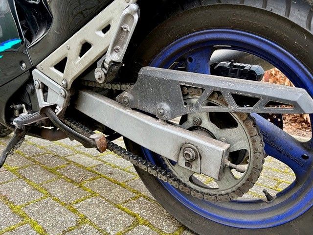 Eine Nahaufnahme einer Motorradkette auf einer Ziegelsteinstraße.