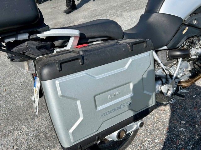 Silberner und schwarzer Motorrad-Seitenkoffer, befestigt an einem schwarzen Motorrad.