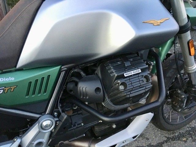 Ein grün-silbernes Motorrad ist am Straßenrand geparkt.