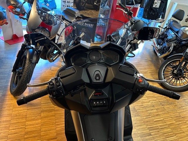 In einem Ausstellungsraum ist ein Motorrad geparkt, umgeben von anderen Motorrädern.