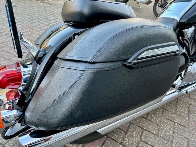 Auf einem gepflasterten Gehweg ist ein schwarzes Motorrad geparkt.