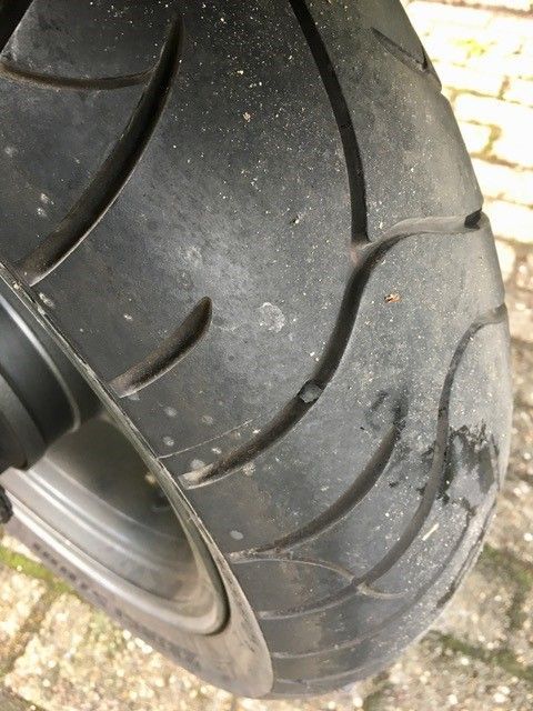 Eine Nahaufnahme eines Motorradreifens auf einer Ziegelsteinstraße.