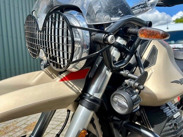 Nahaufnahme der Front eines beigen Motorrads mit rundem Scheinwerfer, schwarzem Kühlergrill und orangefarbenem Blinker