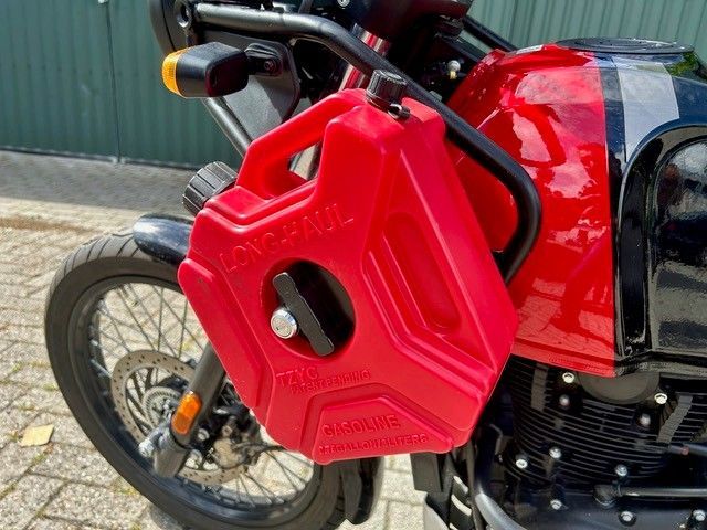 Ein roter Motorrad-Kraftstoffkanister ist neben dem Motor an einem schwarz-verchromten Motorrad montiert.