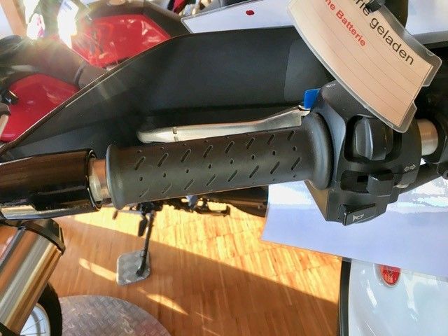 Eine Nahaufnahme des Lenkers eines Motorrads mit einem Schild mit der Aufschrift „Frei geladen“ darauf