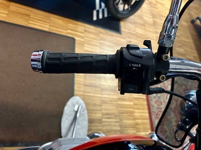 Motorradlenker mit schwarzem Gasgriff und Bedienschalter vor Holzboden