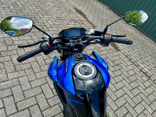 Blaues Motorrad-Armaturenbrett und Lenker, von oben auf einer gepflasterten Auffahrt gesehen