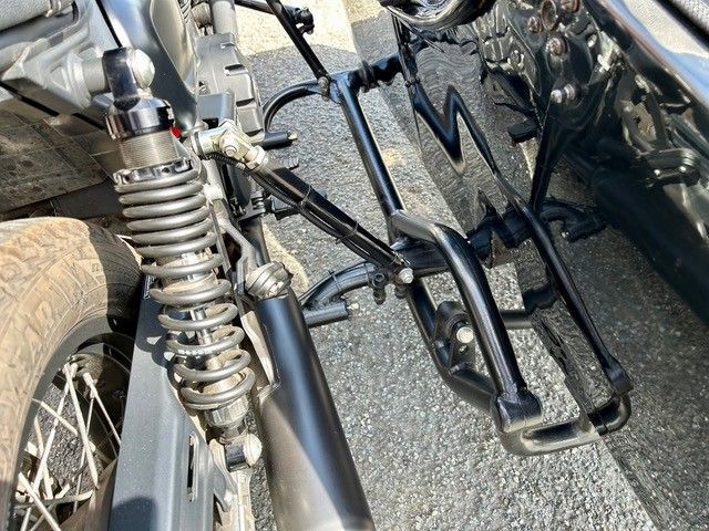 Motorradrahmen mit Stoßdämpfer, Auspuffrohr und Gepäckträger hinten. Schwarz und Silber.