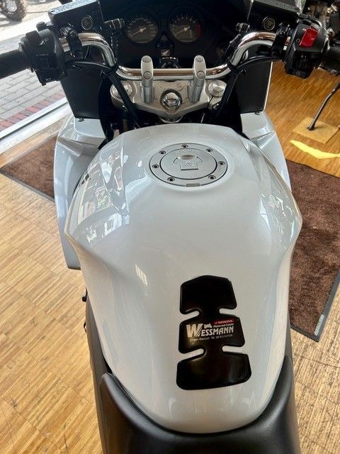 Weißer Motorradtank und Lenker, vom Fahrersitz aus im Innenbereich gesehen