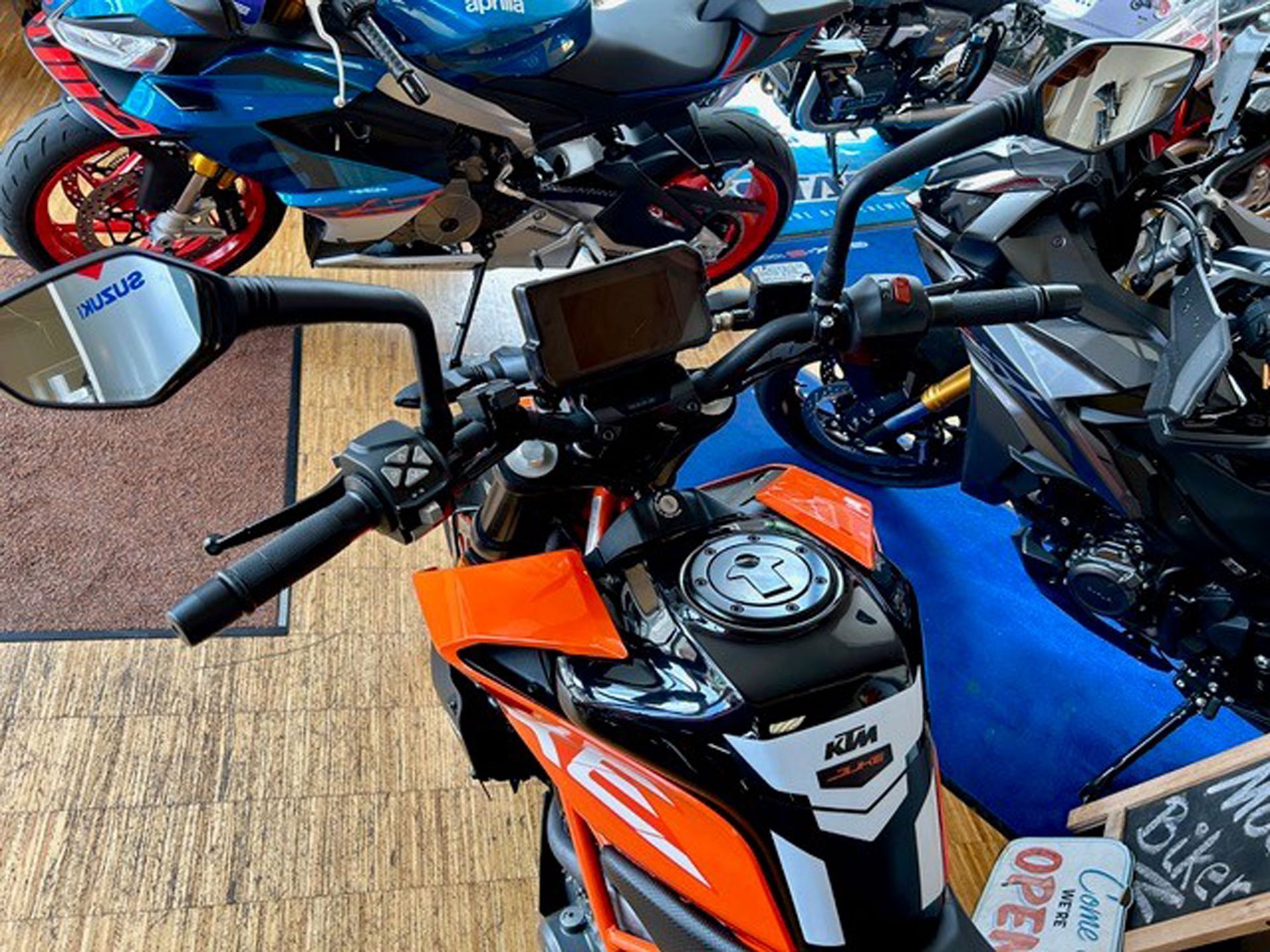 Orange-schwarzes KTM-Motorrad mit sichtbarem Lenker und Kraftstofftank in einem Motorradgeschäft.