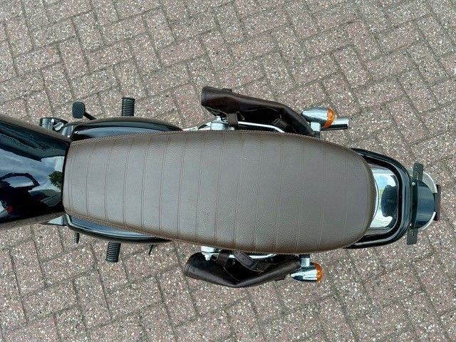Draufsicht auf ein geparktes Motorrad mit beigem Sitz auf einer gepflasterten Fläche