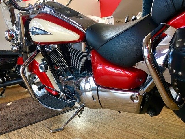 Ein rot-weißes Motorrad ist auf einem Holzboden geparkt