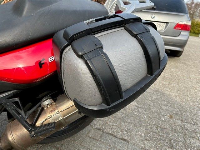 Ein Motorrad ist in einer Einfahrt neben einem BMW geparkt