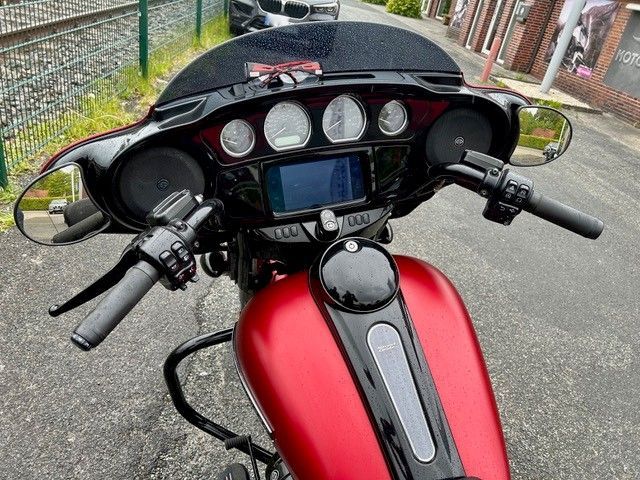 Motorradcockpit mit rotem Kraftstofftank, Instrumenten, Lenker und Handyhalterung auf einem gepflasterten Weg
