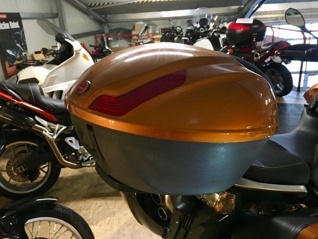 Mehrere Motorräder sind in einer Garage mit einer großen orangefarbenen Box geparkt