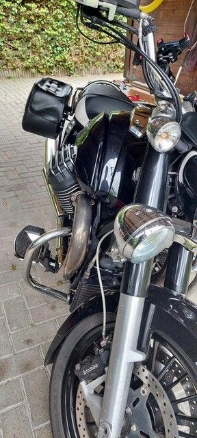 Schwarzes Motorrad mit silbernen Details auf dem Bürgersteig geparkt.