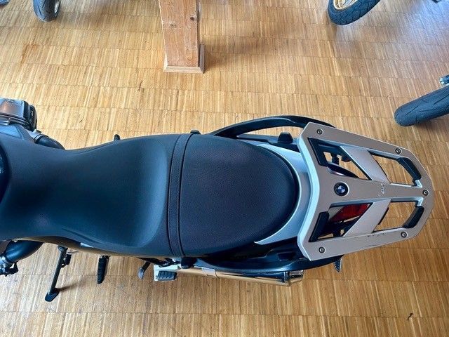 Draufsicht auf einen schwarzen Motorradsitz mit silbernem Gepäckträger auf einem Holzboden