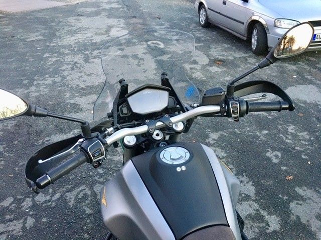 Ein Motorrad steht auf einem Parkplatz neben einem Auto