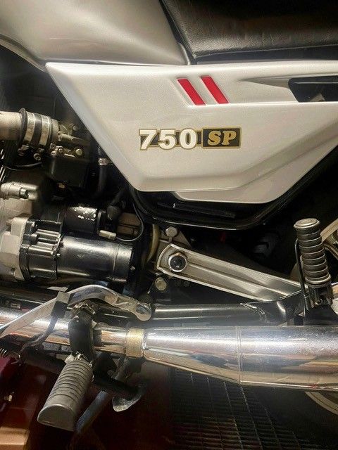 Nahaufnahme der Seitenverkleidung und der verchromten Auspuffrohre eines silbernen Kawasaki 750 SP Motorrads.