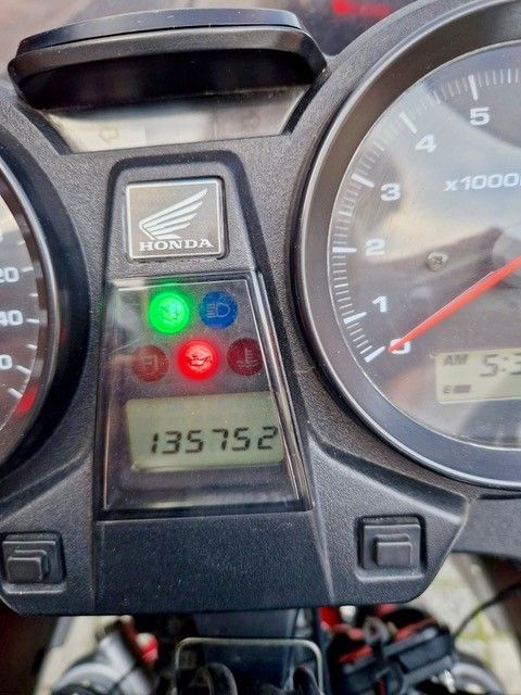 Motorrad-Armaturenbrett mit Kilometerstand 135752, verschiedenen Kontrollleuchten und einem Honda-Logo.