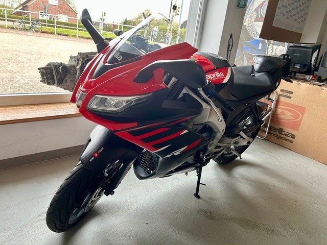 Ein rot-schwarzes Sportmotorrad steht drinnen am Fenster.