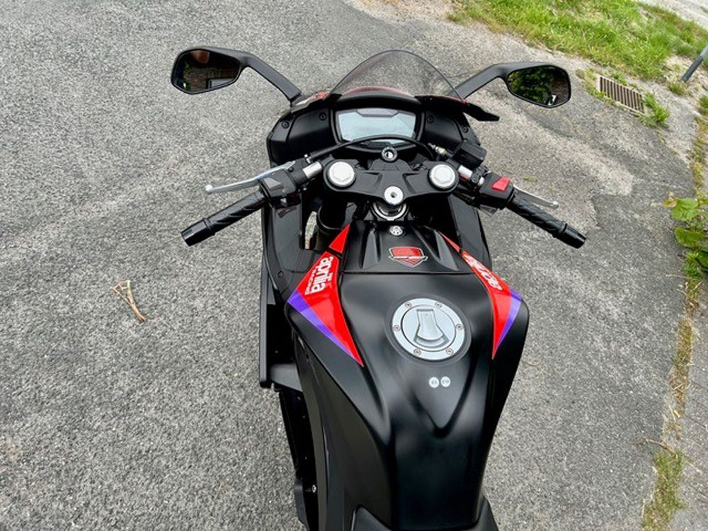 Draufsicht auf ein schwarz-rotes Sportmotorrad, das auf dem Bürgersteig geparkt ist.