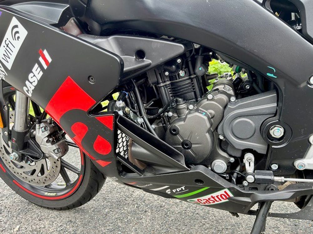 Nahaufnahme der Seite eines schwarz-roten Rennmotorrads, die Motor, Rad und Aufkleber zeigt.