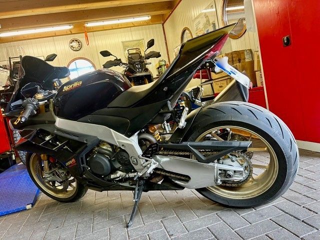 Schwarzes Sportmotorrad in einer Garage geparkt, Seitenansicht mit roten Wänden und anderen Motorrädern im Hintergrund