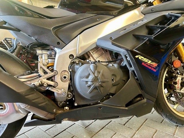 Nahaufnahme des freiliegenden Motors und der Seitenverkleidung eines schwarzen Sportmotorrads in einer Garage, das Hinterrad ist sichtbar.