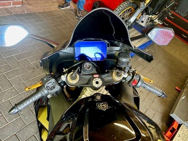 Draufsicht auf ein schwarzes Sportmotorrad mit blau beleuchtetem Armaturenbrett in einer Garage.