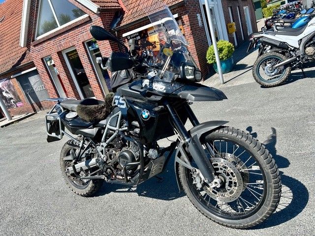 Vor einem Backsteingebäude parkt ein schwarzes Motorrad.