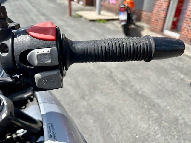 Motorradlenker mit schwarzem Griff und Bedienelementen, Nahaufnahme im Freien.