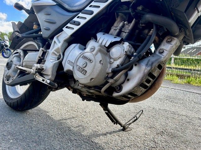 Nahaufnahme eines silbernen Yamaha-Motorradmotors auf einem geparkten Motorrad mit ausgeklapptem Seitenständer.