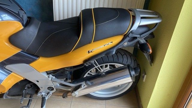 Ein gelb-schwarzes Motorrad ist neben einer Mauer geparkt.
