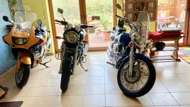 Drei Motorräder sind in einem Raum nebeneinander geparkt.