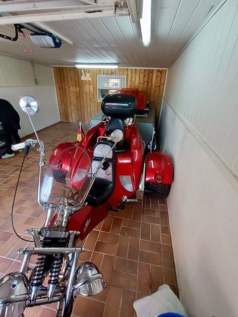 Ein rotes dreirädriges Motorrad steht in einer Garage