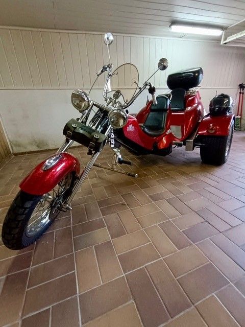 Ein rotes Motorrad mit drei Rädern steht in einer Garage.