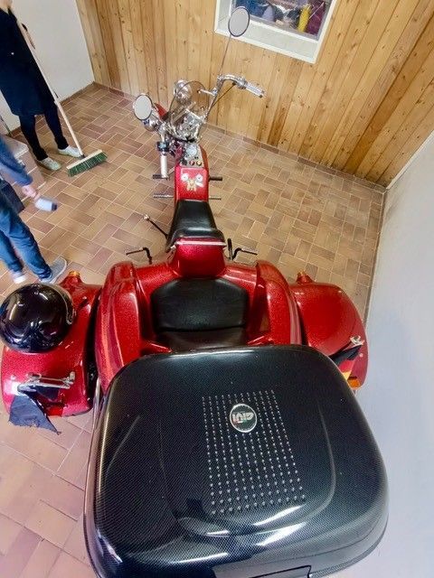 Ein rotes Motorrad steht in einer Garage neben einer Blackbox