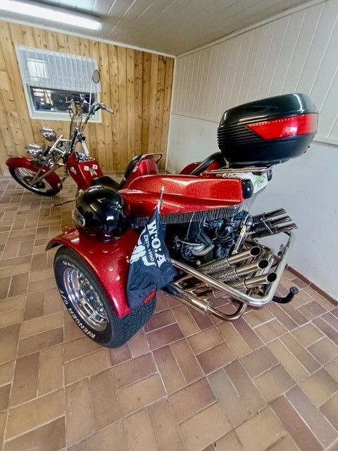 Ein rotes Motorrad mit drei Rädern steht in einer Garage.