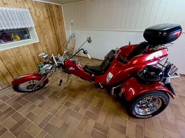 Ein rotes Motorrad mit drei Rädern steht in einer Garage