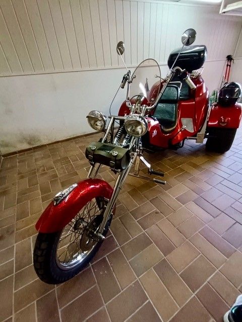 Ein rotes Motorrad mit drei Rädern steht in einer Garage