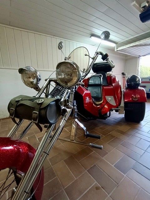 Ein rotes Motorrad mit drei Rädern steht in einer Garage