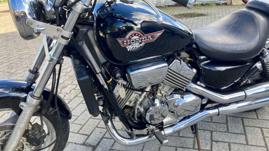 Schwarzes Honda Shadow-Motorrad, glänzendes Chrom, im Freien geparkt.