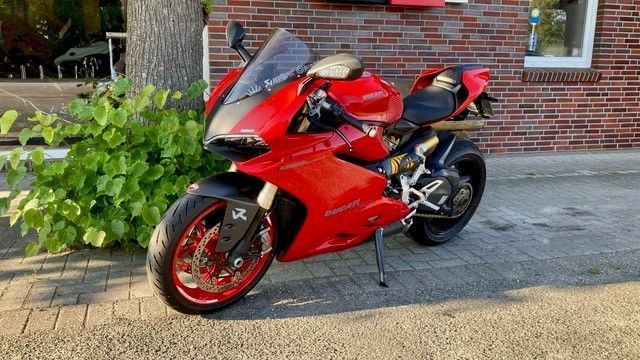 Vor einem Backsteingebäude parkt ein rotes Motorrad.