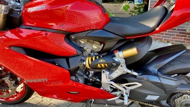 Vor einem Backsteingebäude parkt ein rotes Ducati-Motorrad.