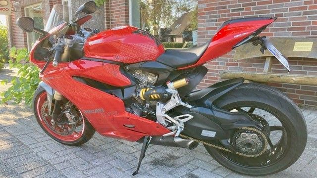 Vor einem Backsteingebäude parkt ein rotes Motorrad.