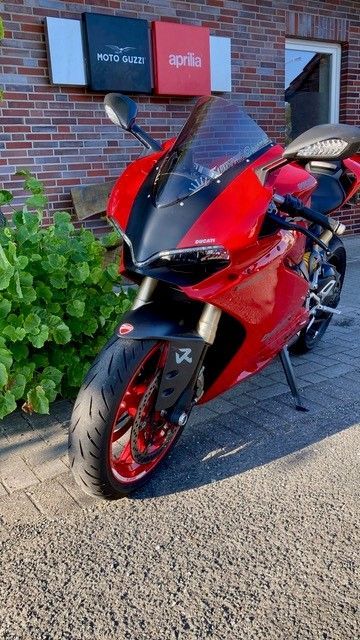 Vor einem Backsteingebäude parkt ein rot-schwarzes Motorrad.
