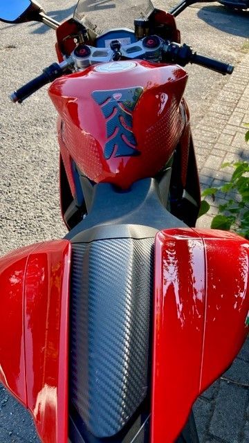 Ein rotes Motorrad steht am Straßenrand