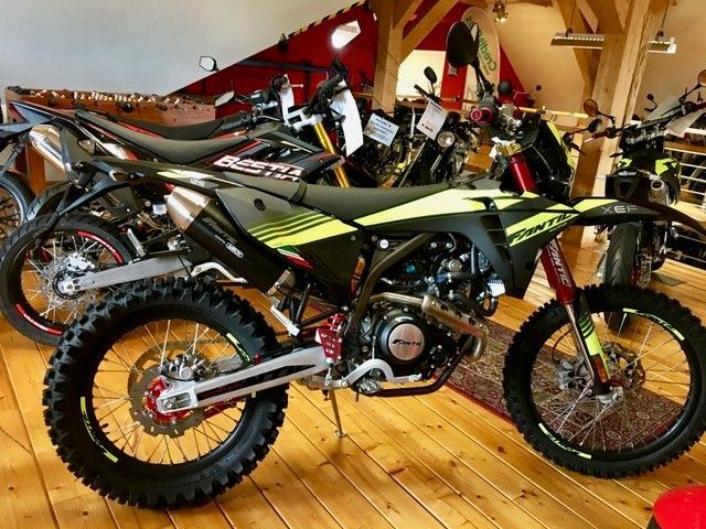 Ein Dirtbike steht auf einem Holzboden in einem Ausstellungsraum.